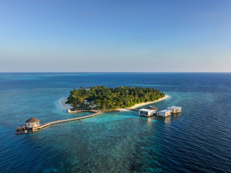 The small island, its jetty and overwater villas, from the air