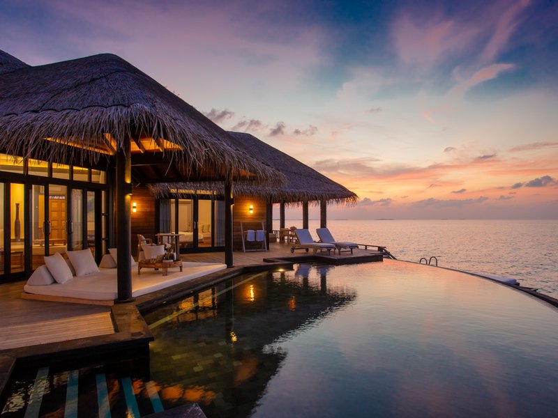 An overwater residence with an infinity pool, at sunset