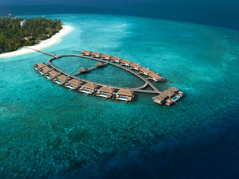 An arc of overwater villas over the reef, from high above