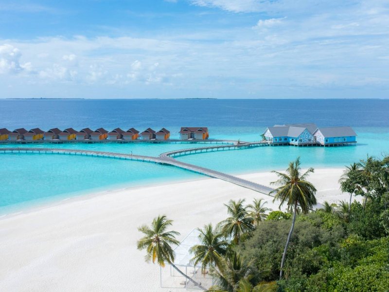 Overwater villas and a long jetty beyond a white beach, from the air