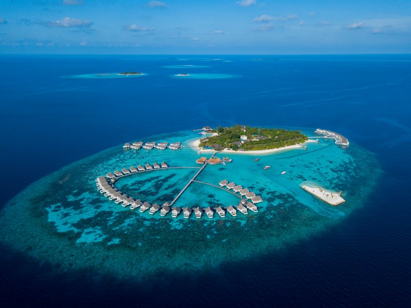 The island and its arcs of overwater villas, from high above