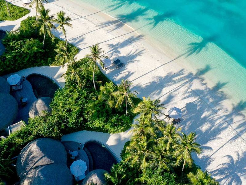 Trees, villas and a beach of white sand, from above