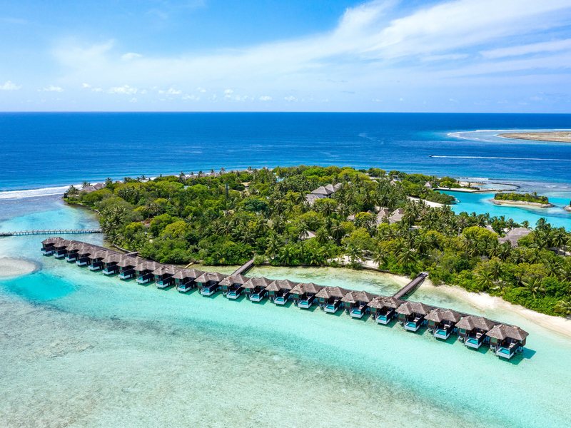 The island and its long row of water villas, from the air