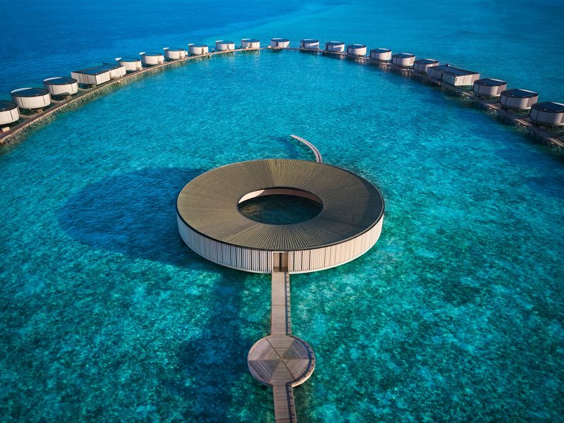 A ring-shaped spa over the lagoon, with a curve of overwater villas behind