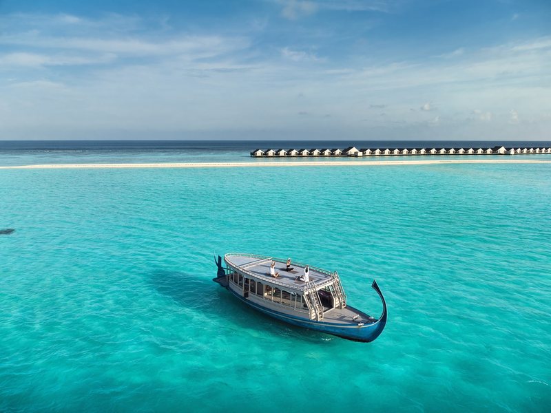 A dhoni on the lagoon, with overwater villas beyond