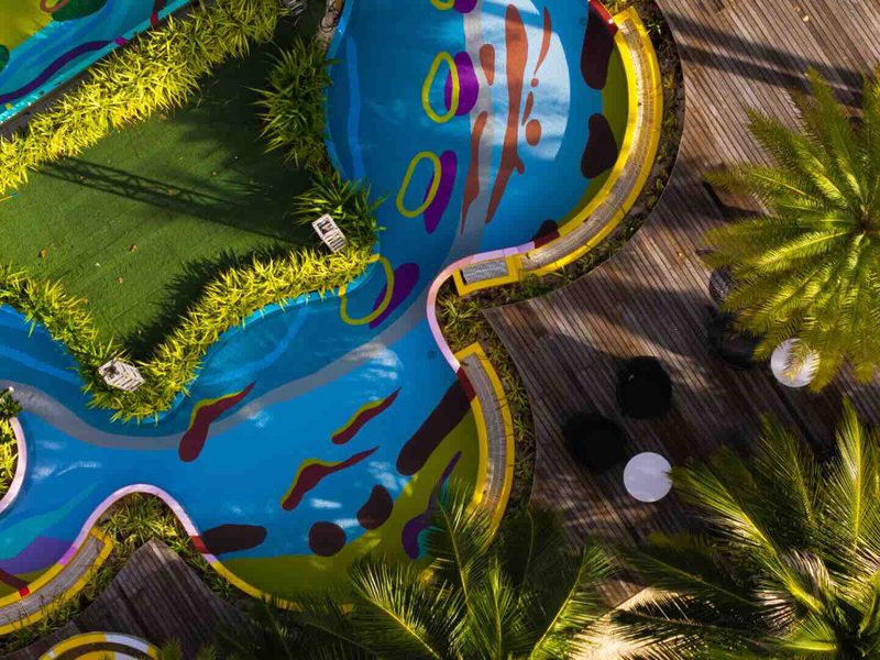 A painted swimming pool among palms, from directly above