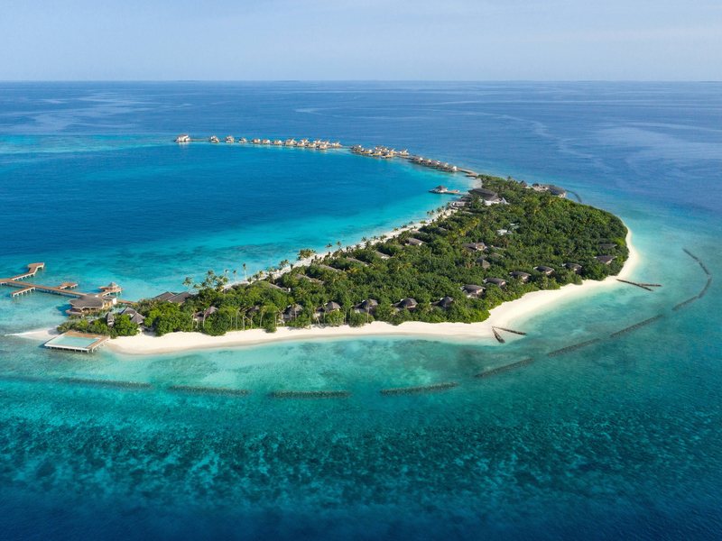 The curving island and its water villas, from the air