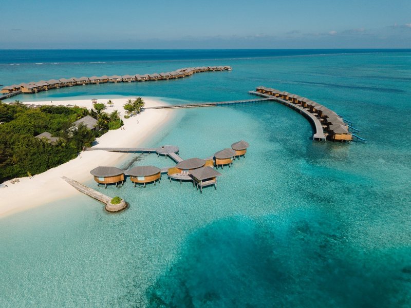 Thatched water villas in clusters and long rows, from the air
