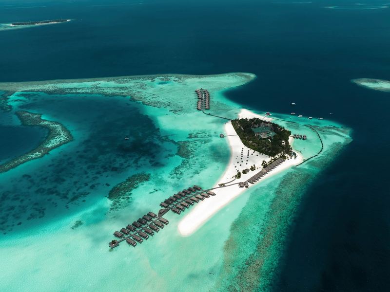 The island, its sandbank and overwater villas, from the air