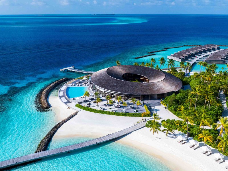 A round spa building, beach and water villas, from the air