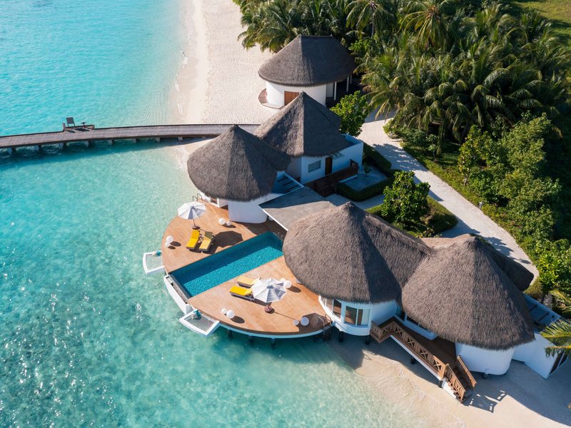 Thatched pool villas at the lagoon’s edge, from the air