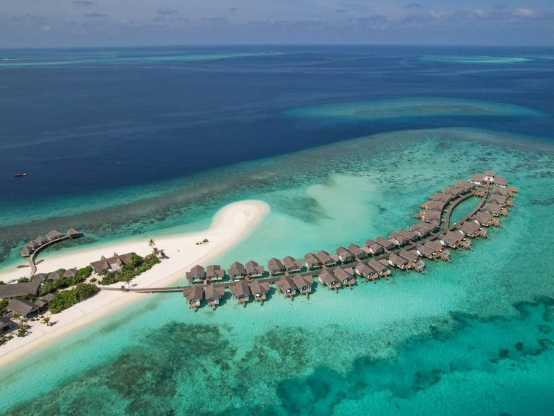 A sandbank and a long arc of overwater villas, from high above
