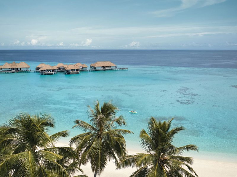 Palms and the beach, with water villas on the lagoon beyond