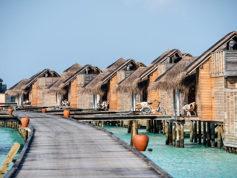 Thatched overwater villas along a wooden walkway