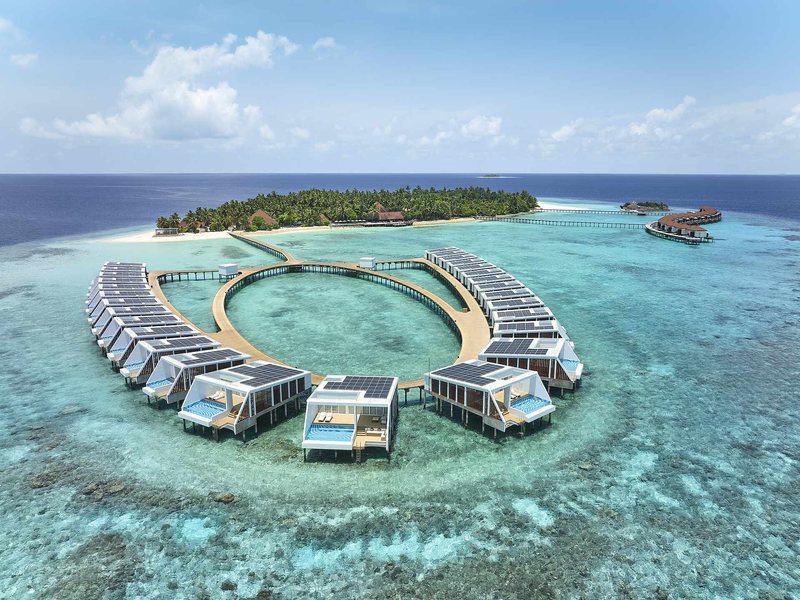 A ring of water villas over the reef, with the island behind