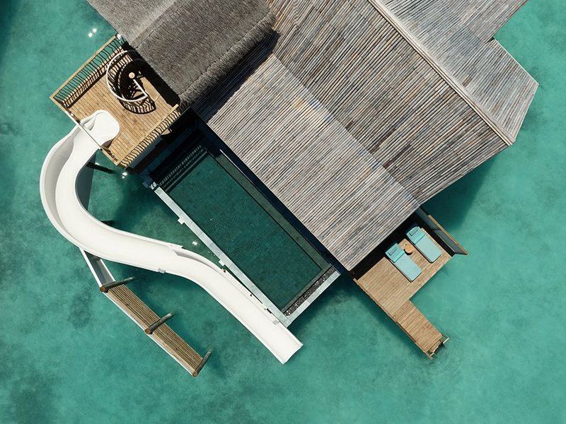 A water villa with its own pool and a slide into the lagoon, from above