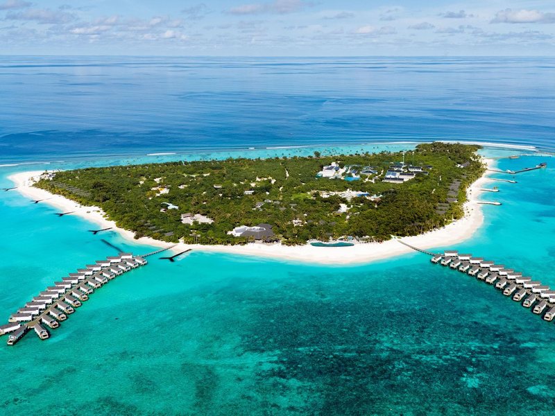 The island and its two arms of overwater villas, from the air
