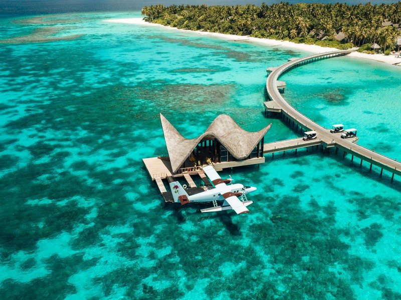 A sculptural arrival pavilion with a seaplane, the island behind