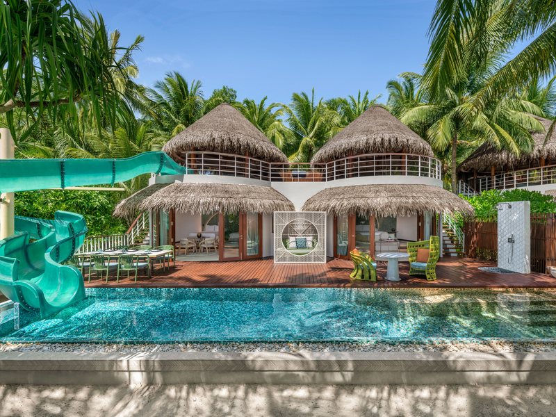 A thatched two-storey villa with a slide into its pool