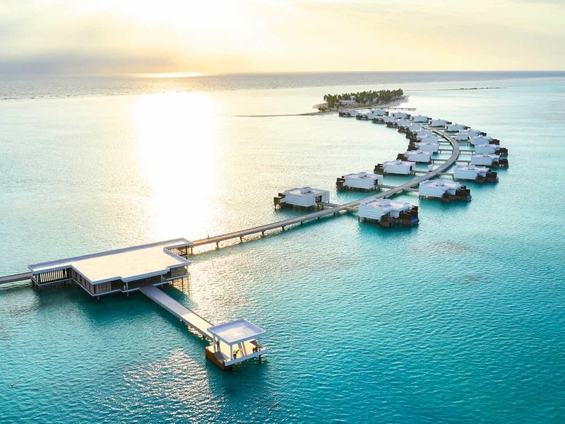 Overwater suites along a curving jetty, at sunset