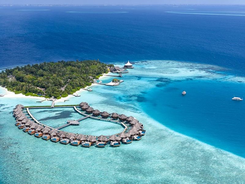 The island and a ring of overwater villas, from the air