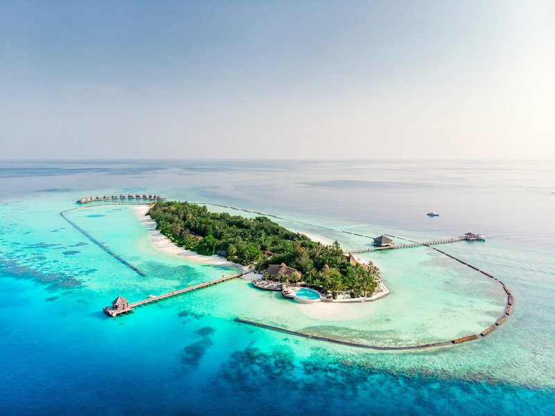 The island, its jetties and arc of water villas, from the air