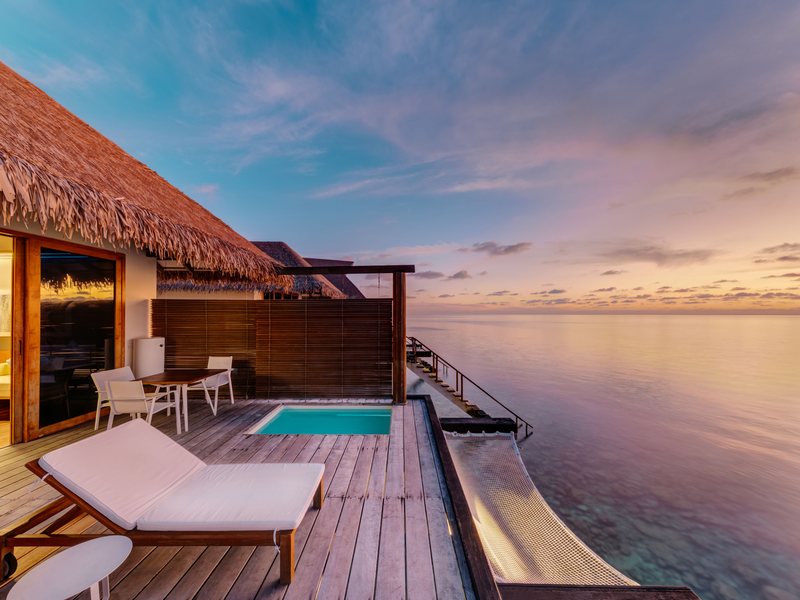 A water villa deck with a plunge pool, at sunset