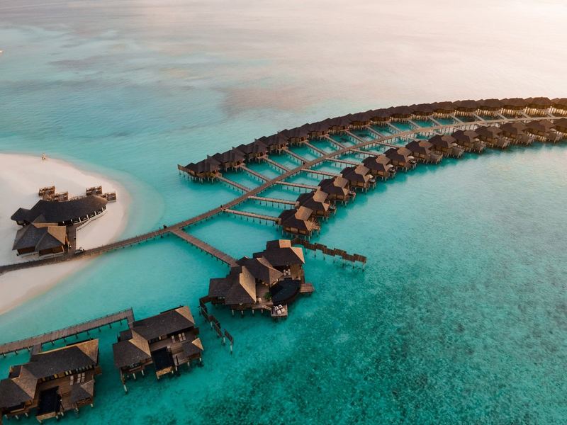 Overwater villas along a curving jetty, at sunset