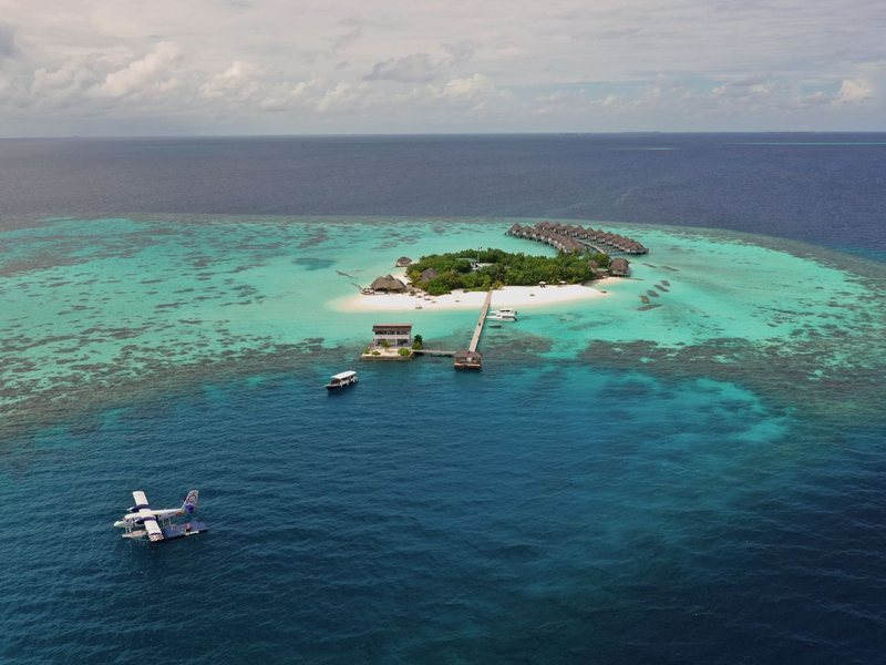 The tiny island in its reef, with a seaplane, from the air