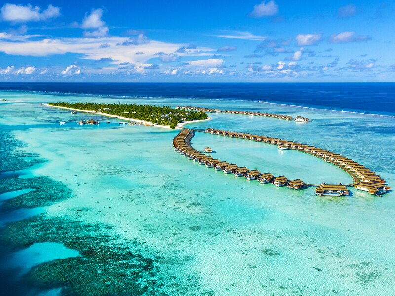 The island and a loop of overwater villas, from the air