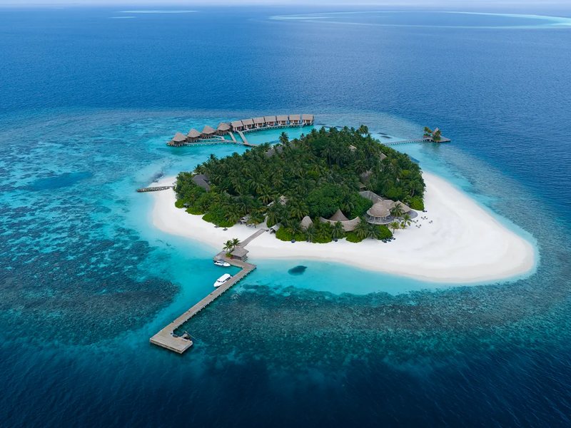 The small island, its jetty and water villas, from the air