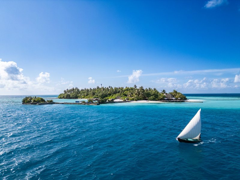 The island across the sea, with a sailing dhoni in front