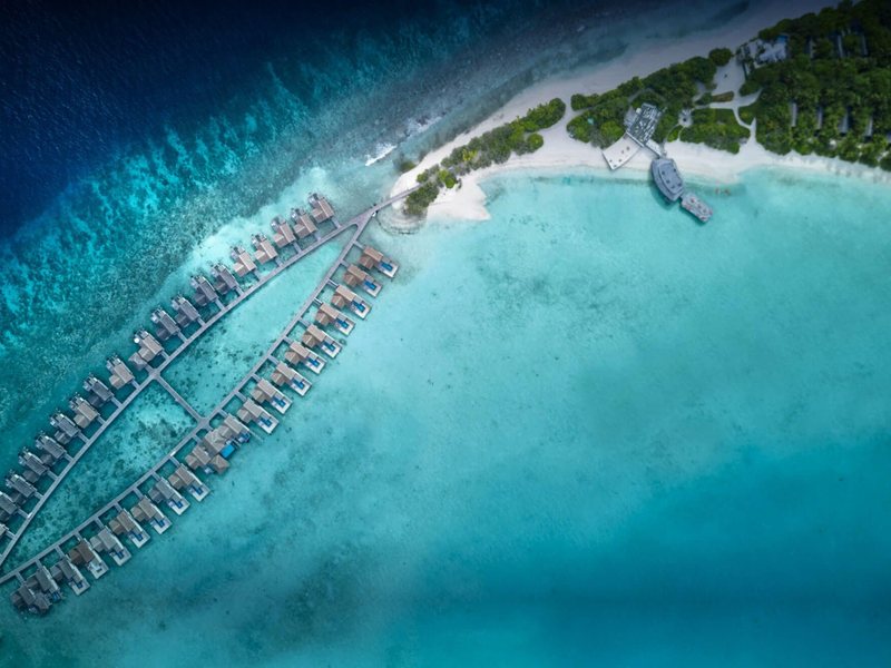 Curving rows of overwater villas off the beach, from high above