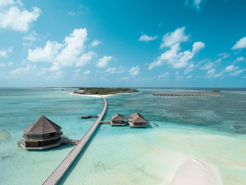 A long walkway to an overwater restaurant and water villas, from the air